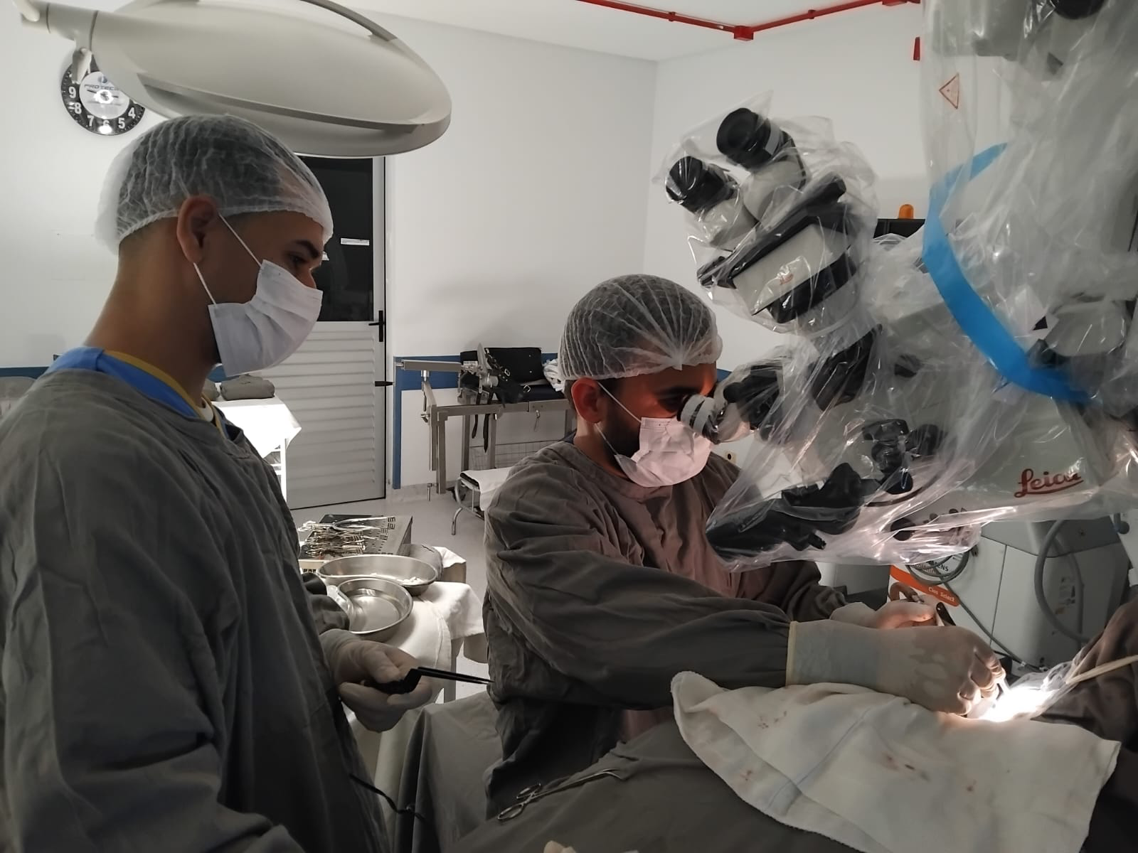 Cirurgião operando ao lado do microscópio cirúrgico